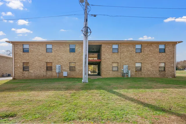 a view of a brick house with a big yard and large tree