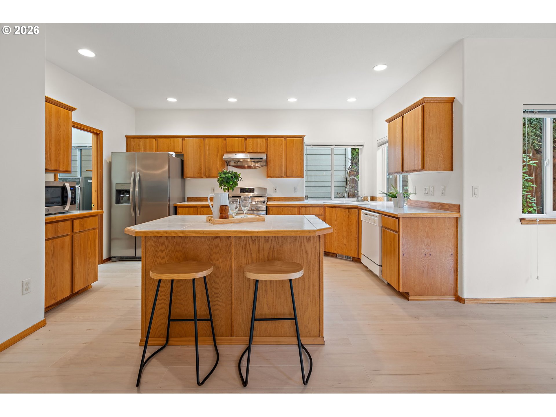 15460 Southwest 145th Terrace Tigard, OR 97224 - Photo 21 of 45 a dining hall with stainless steel appliances kitchen island granite countertop a table chairs and a refrigerator