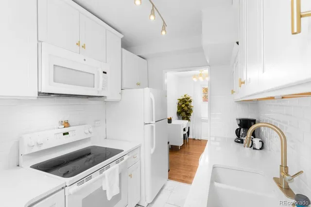 a kitchen with stainless steel appliances white cabinets a stove a sink and a refrigerator