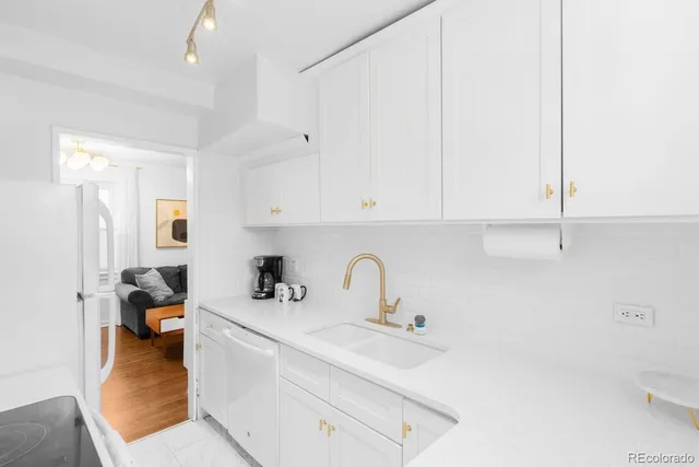 a kitchen with stainless steel appliances a sink a stove and white cabinets