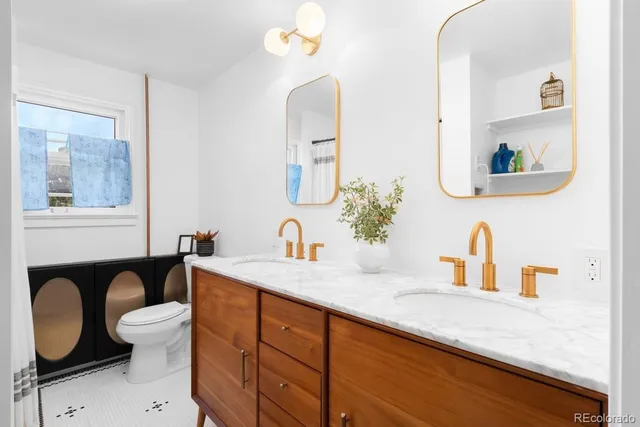 a bathroom with a granite countertop sink a toilet a mirror and a window