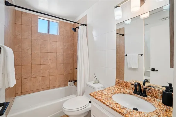a bathroom with a granite countertop sink a mirror a bathtub and shower