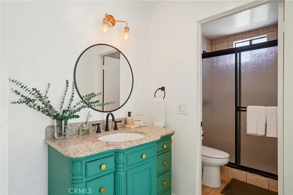 a bathroom with a granite countertop sink a toilet and a mirror