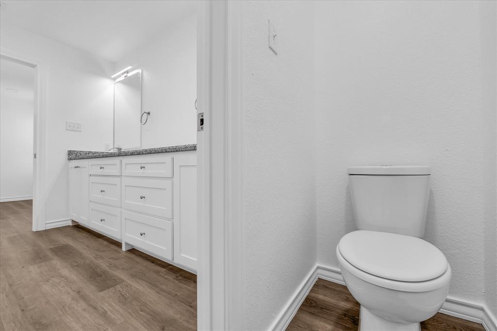 204 North Wiebusch Street Riesel, TX 76682 - Photo 18 of 33 a bathroom with a toilet a sink a vanity and mirror