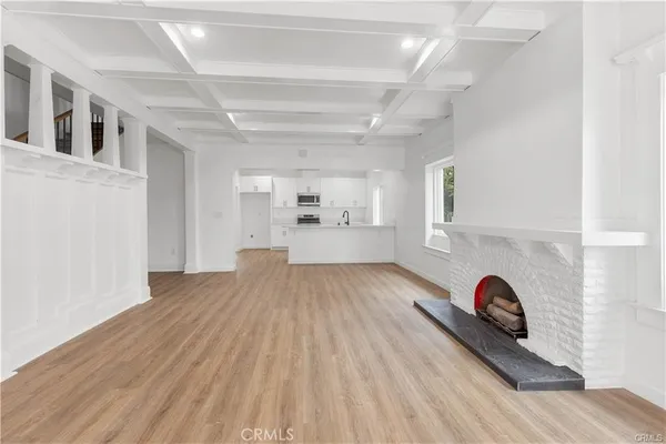 a view of kitchen and empty room with wooden floor
