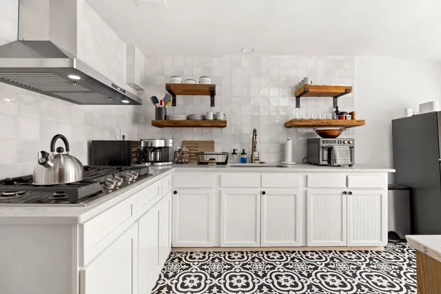 a kitchen with stainless steel appliances a sink a stove and white cabinets