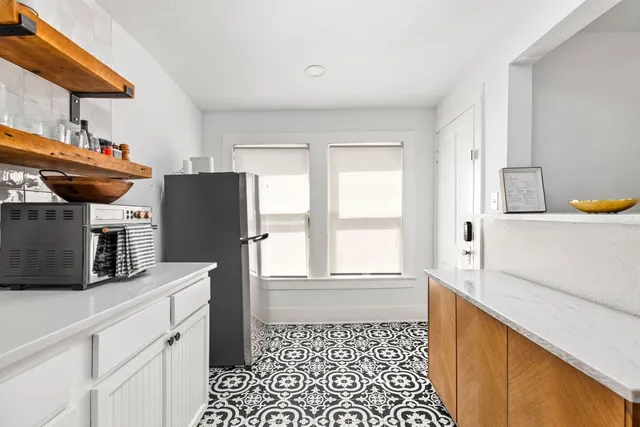 a kitchen with stainless steel appliances a refrigerator a sink a stove and white cabinets