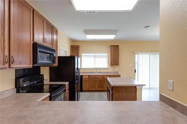 a kitchen with granite countertop a refrigerator stove top oven and sink