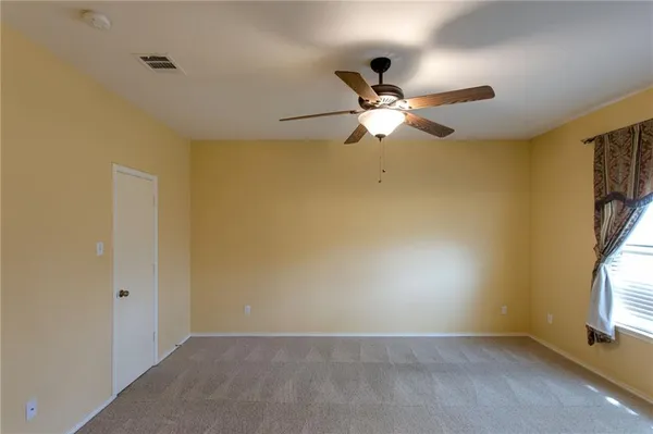 an empty room with a ceiling fan and a window