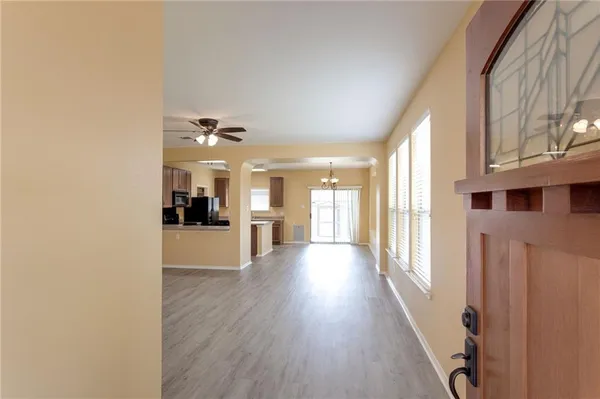 a view of a hallway with wooden floor and a kitchen
