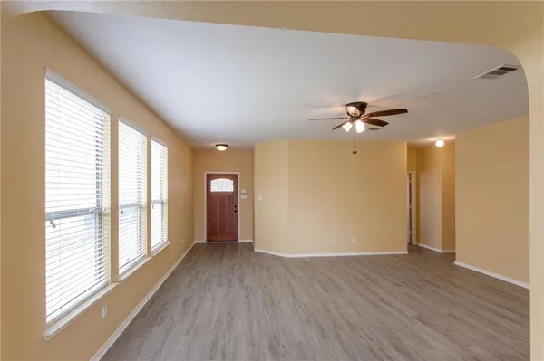 a view of an empty room with a window and wooden floor