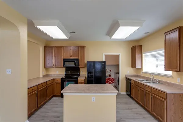 a kitchen with kitchen island a refrigerator stove a sink and dishwasher wooden cabinets