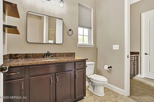 a bathroom with a granite countertop toilet sink and mirror
