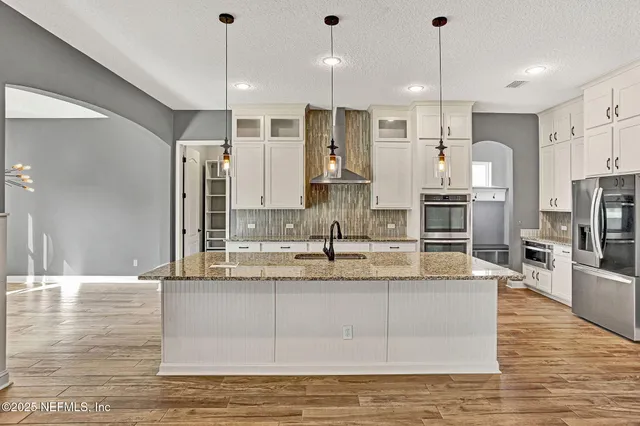 a large kitchen with kitchen island a large counter top stainless steel appliances and cabinets