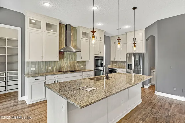 a kitchen with stainless steel appliances granite countertop a sink a refrigerator and a stove