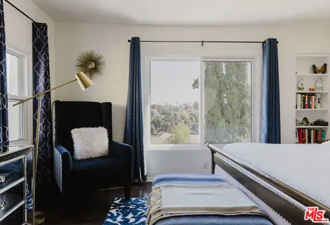 a bedroom with a bed lamp and a large window