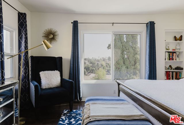 a bedroom with a bed lamp and a large window