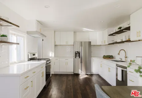 a kitchen with stainless steel appliances a white table chairs and a wooden floor