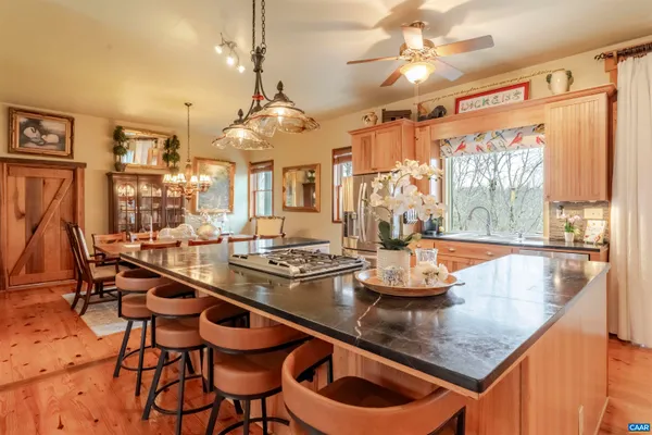 a kitchen with stainless steel appliances granite countertop a stove a sink a dining table and chairs with wooden floor