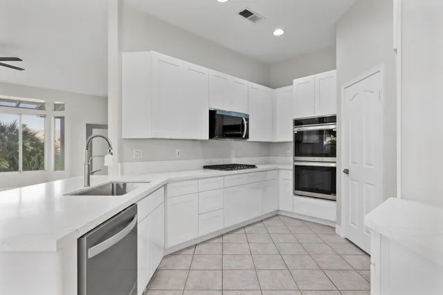 a kitchen with stainless steel appliances a sink a stove a refrigerator and cabinets