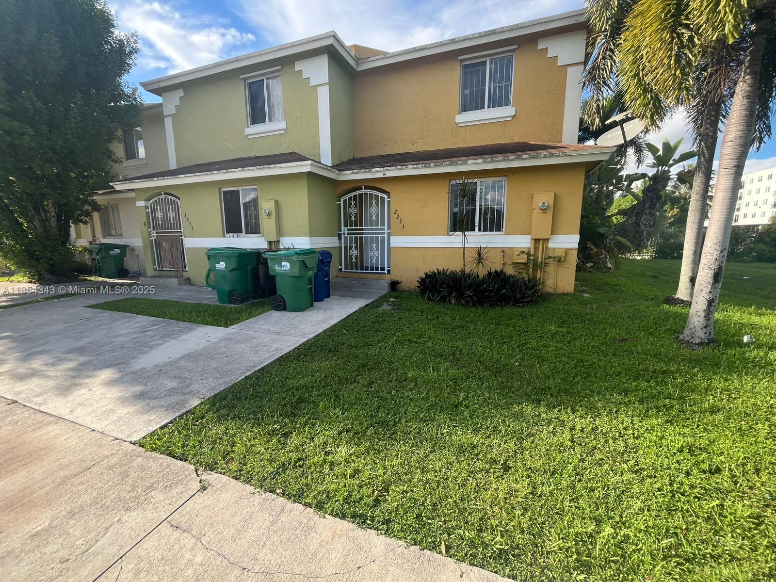 2251 Northwest 136th Terrace, Unit 2251 Opa-Locka, FL 33054 - Photo 20 of 20 a view of a white house next to a yard with big trees