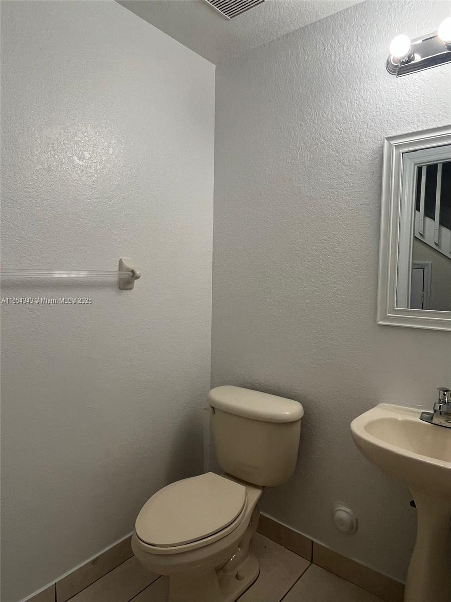 2251 Northwest 136th Terrace, Unit 2251 Opa-Locka, FL 33054 - Photo 5 of 20 a white toilet sitting next to a bathroom sink