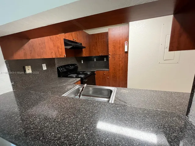 a kitchen with a sink a stove and a wooden cabinets