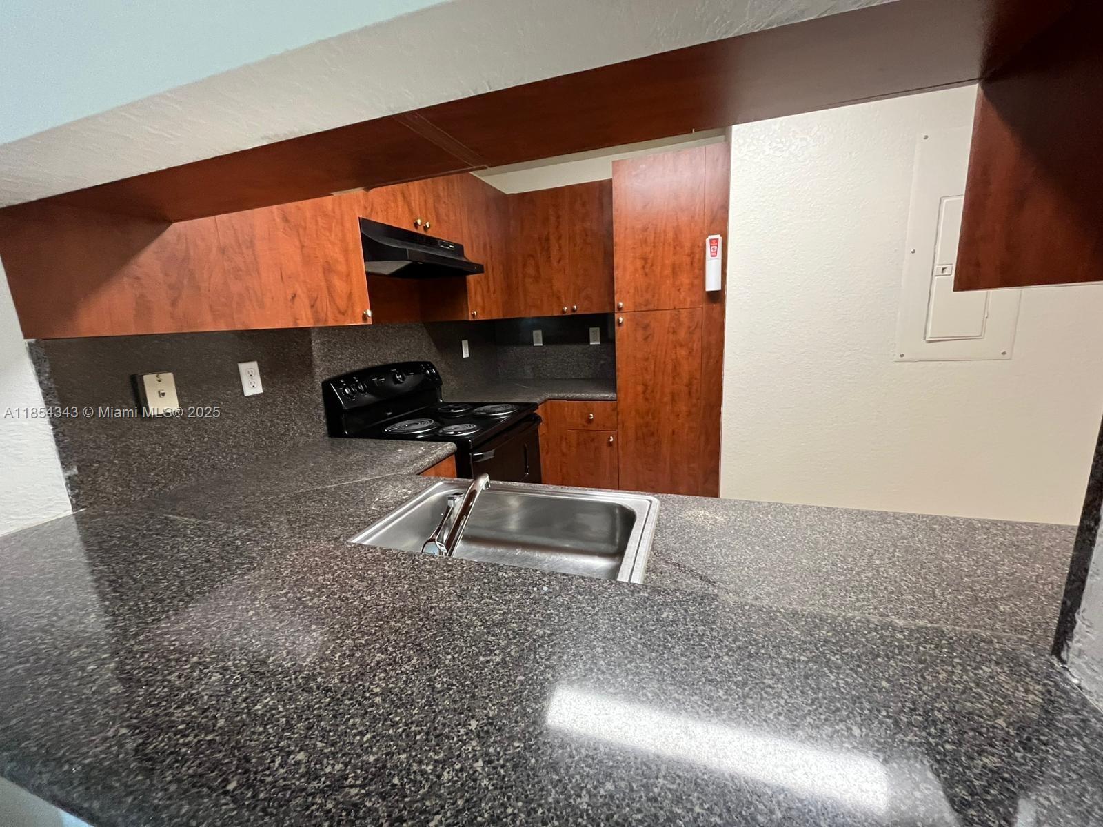 2251 Northwest 136th Terrace, Unit 2251 Opa-Locka, FL 33054 - Photo 7 of 20 a kitchen with a sink a stove and a wooden cabinets