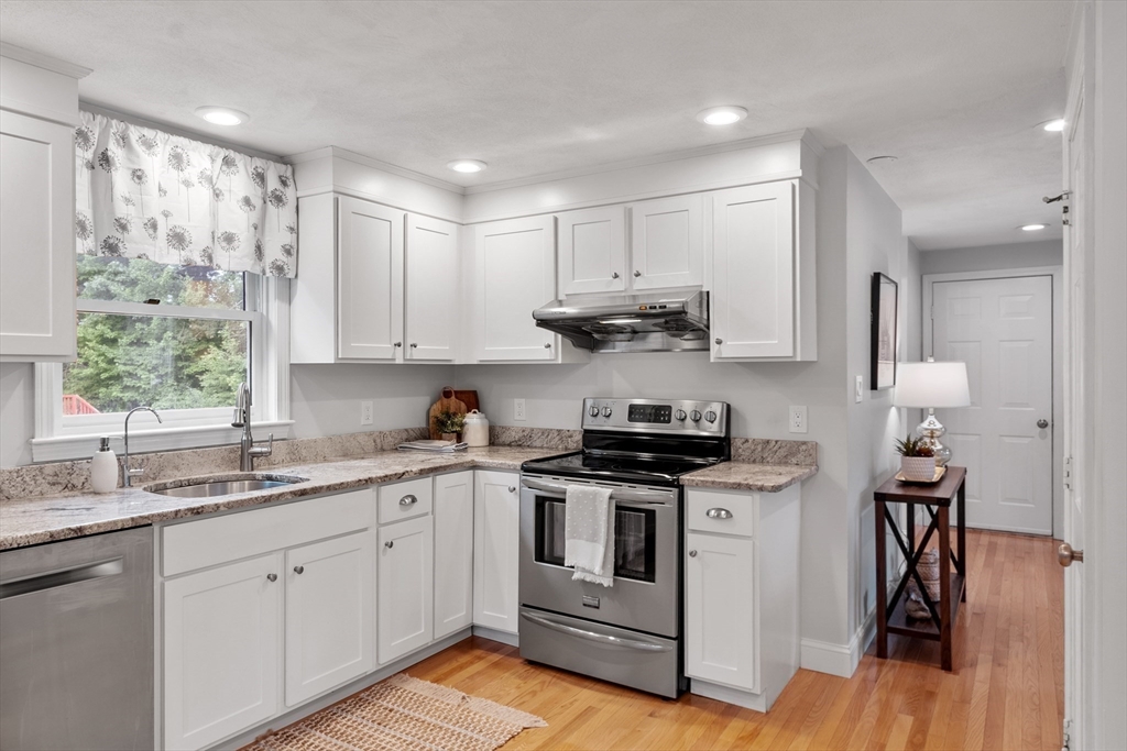 106 Reed Farm Road Boxborough, MA 01719 - Photo 5 of 40 a kitchen with stainless steel appliances granite countertop a stove a sink dishwasher and white cabinets with wooden floor