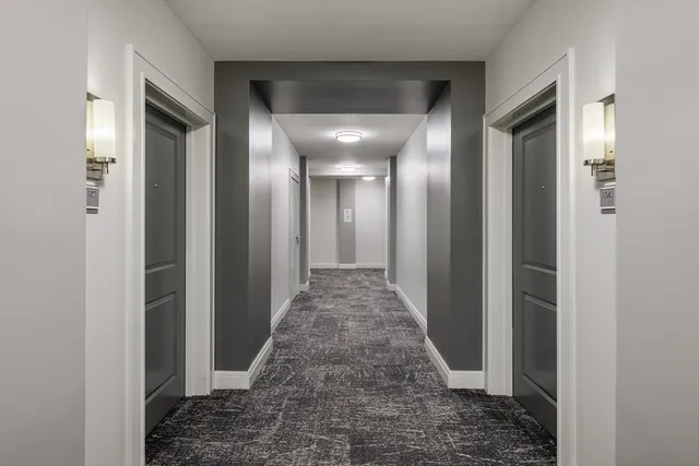 a view of a hallway with wooden floor and a bathroom