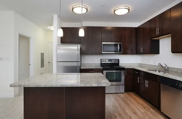 a kitchen with granite countertop a refrigerator and a stove top oven