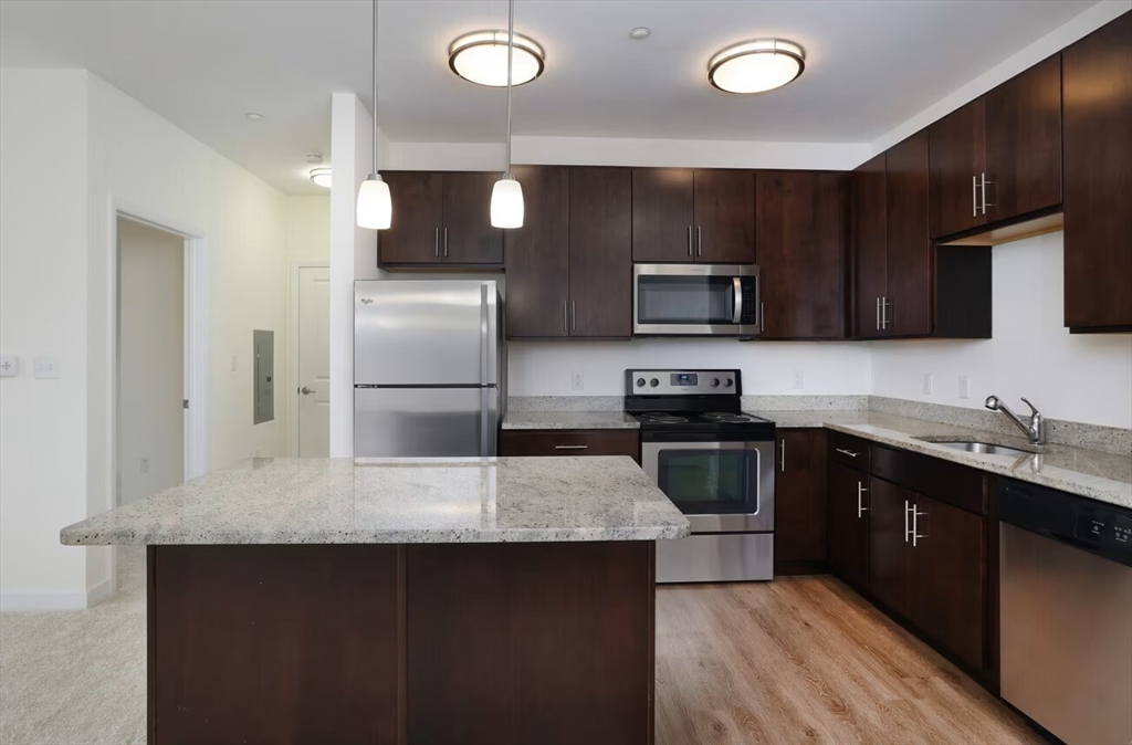 30 Mill Street, Unit 105 Arlington, MA 02476 - Photo 15 of 33 a kitchen with granite countertop a refrigerator and a stove top oven