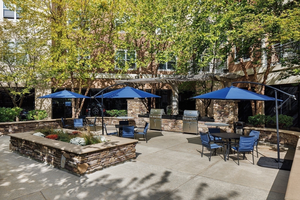 30 Mill Street, Unit 105 Arlington, MA 02476 - Photo 4 of 33 a backyard of a house with barbeque oven table and chairs