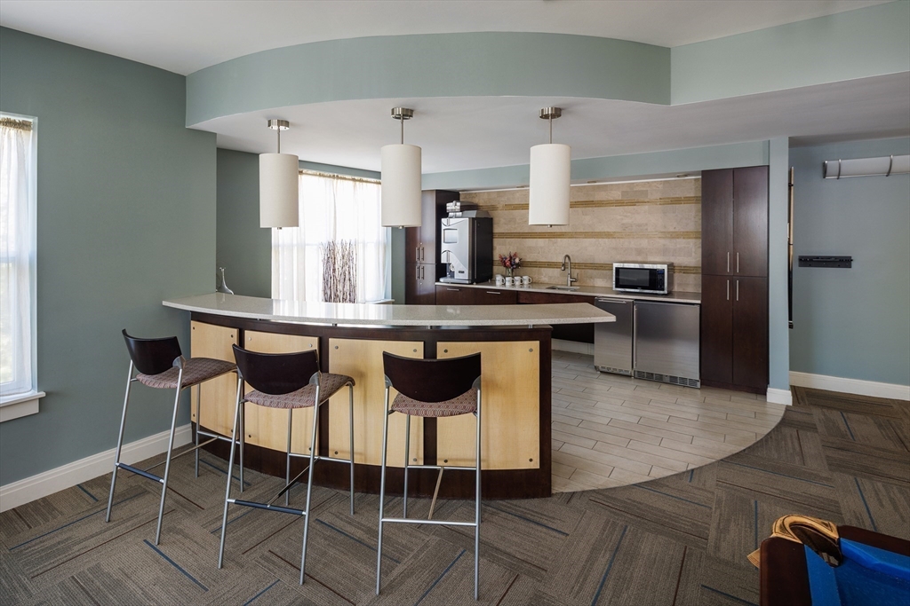 30 Mill Street, Unit 105 Arlington, MA 02476 - Photo 8 of 33 a kitchen with stainless steel appliances kitchen island granite countertop a table chairs and a refrigerator