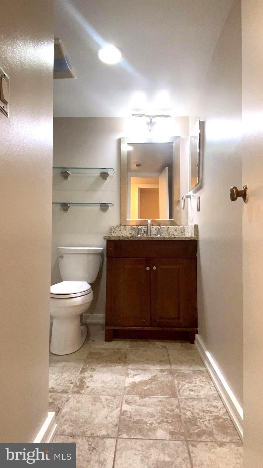 11839 Shire Court, Unit 2C Reston, VA 20191 - Photo 28 of 60 a bathroom with a granite countertop sink a toilet and a mirror