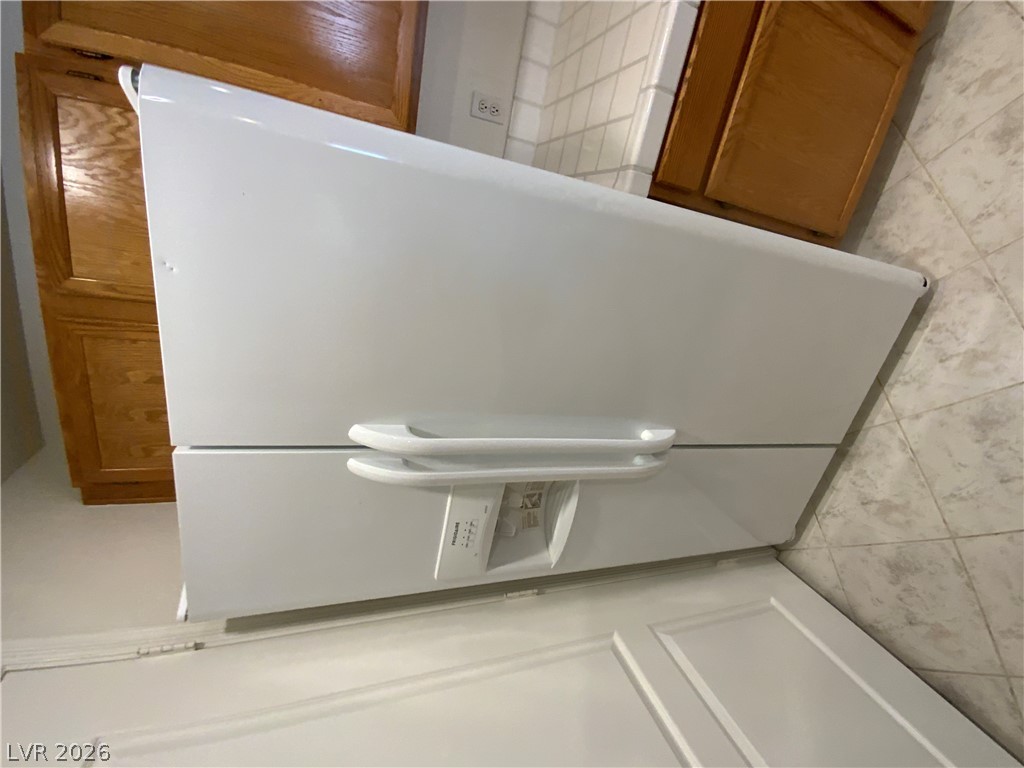 7400 West Flamingo Road, Unit 1039 Las Vegas, NV 89147 - Photo 20 of 40 White kitchen appliances complement wood cabinetry and tiled flooring, perfect for daily culinary routines.