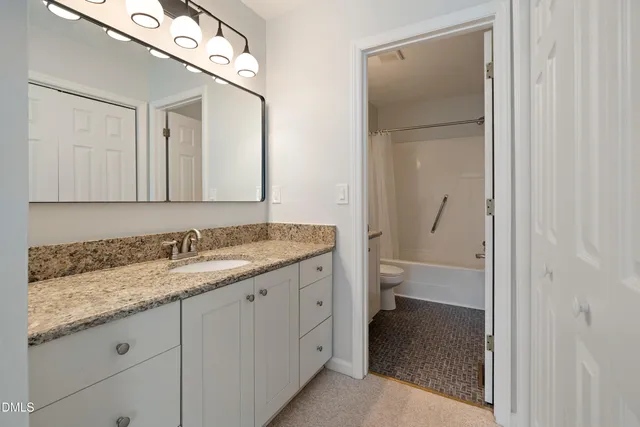 a bathroom with a granite countertop sink a toilet and a mirror