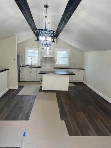 a living room with stainless steel appliances kitchen island a chandelier