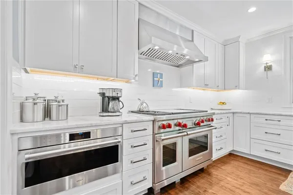a kitchen with stainless steel appliances a stove and white cabinets
