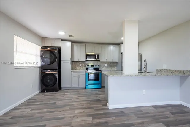 a kitchen with granite countertop a refrigerator stove and wooden floor