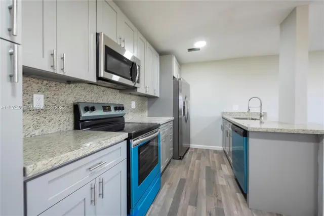a kitchen with stainless steel appliances granite countertop a sink stove and microwave