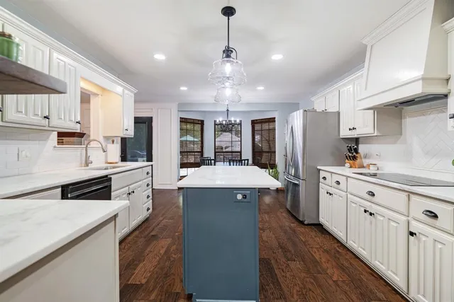 a kitchen with granite countertop a sink dishwasher a refrigerator and white cabinets with wooden floor