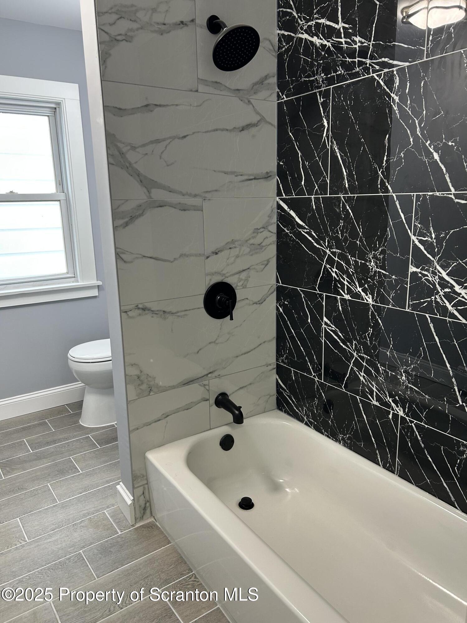 99 Washington Street Carbondale, PA 18407 - Photo 12 of 20 a bathroom with a white bathtub and a shower