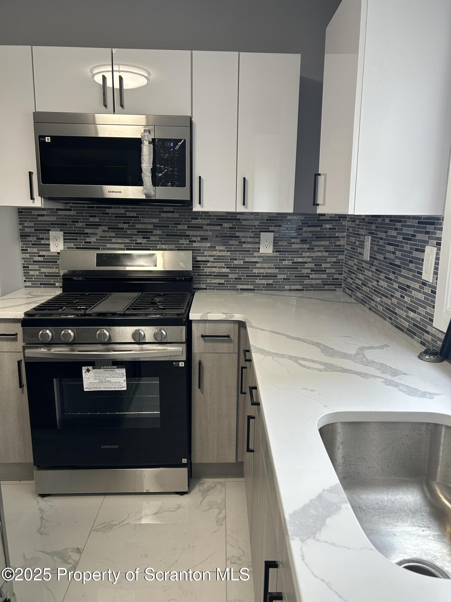 99 Washington Street Carbondale, PA 18407 - Photo 6 of 20 a kitchen with granite countertop a stove and a microwave