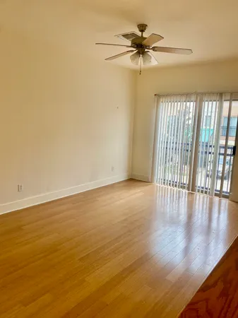 a view of an empty room with a window and wooden floor