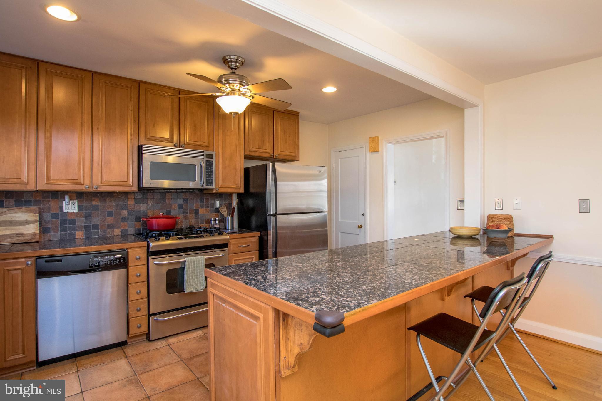 128 Overbrook Road Baltimore, MD 21212 - Photo 5 of 29 a kitchen with kitchen island granite countertop wooden cabinets and stainless steel appliances