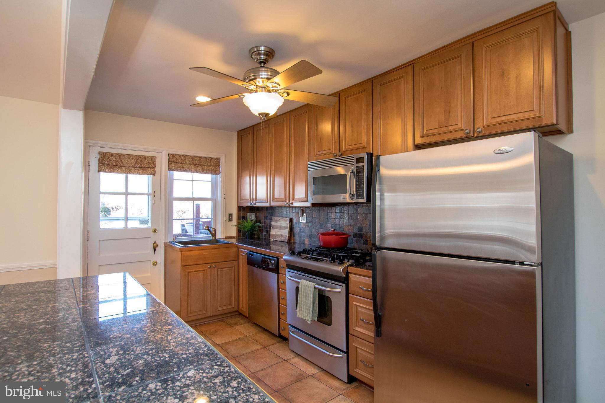 128 Overbrook Road Baltimore, MD 21212 - Photo 6 of 29 a kitchen with stainless steel appliances granite countertop a refrigerator a sink dishwasher a stove and white countertops with wooden floor