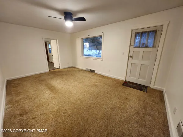an empty room with windows and ceiling fan
