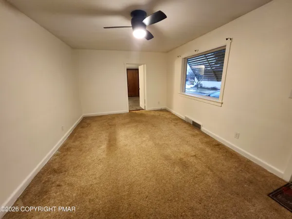 an empty room with windows and fan