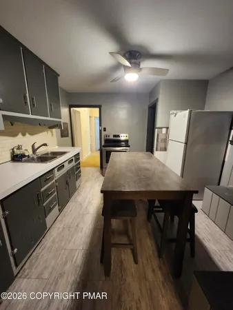 a kitchen with granite countertop a stove a sink dishwasher a dining table and chairs with wooden floor